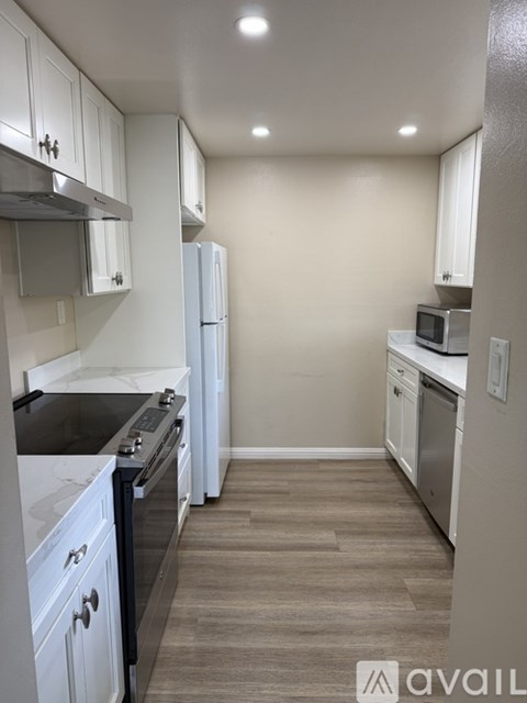 A kitchen with white cabinets and a black stove top.