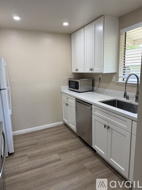 A kitchen with white cabinets and a white fridge.