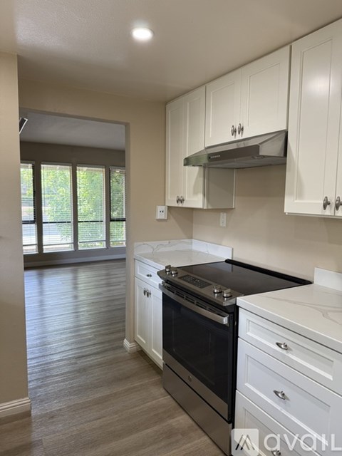 A kitchen with white cabinets and a black countertop.