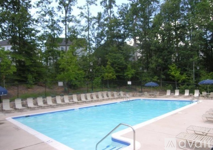 A pool surrounded by trees and chairs.