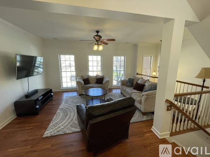 A living room with a brown leather couch and a flat screen TV mounted on the wall.