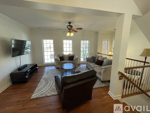 A living room with a brown leather couch and a flat screen TV mounted on the wall.