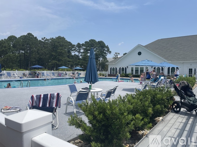 A poolside area with people relaxing and a baby stroller.