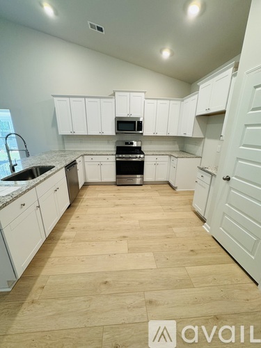 A kitchen with white cabinets and wooden flooring.