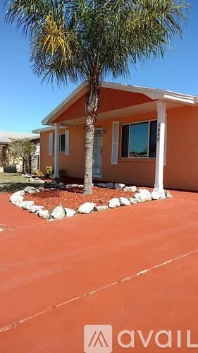 A small orange house with a palm tree in front.