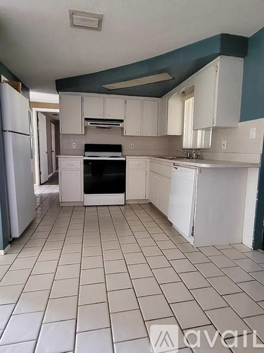 A kitchen with white cabinets and a white refrigerator.