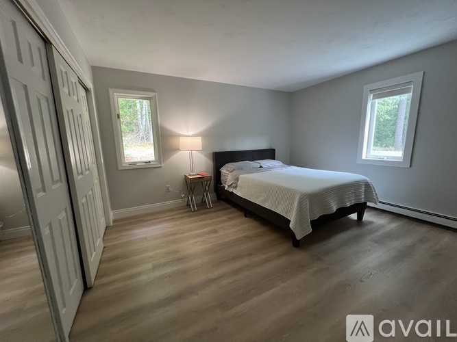 A bedroom with a bed, a chair, and a window.