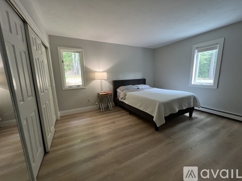 A bedroom with a bed, a chair, and a window.