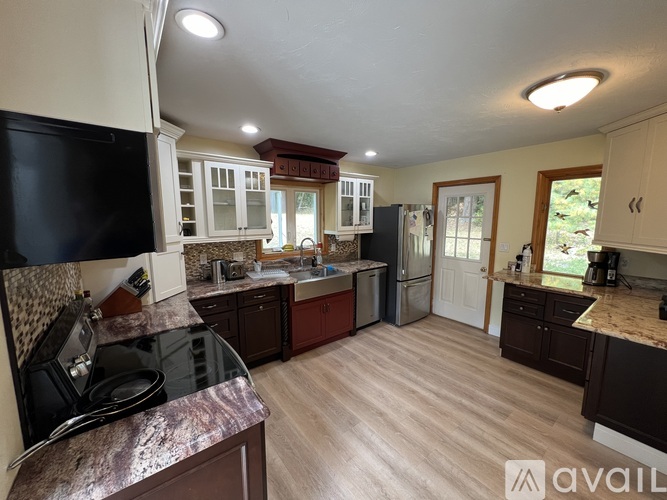 A kitchen with a black refrigerator and wooden cabinets.