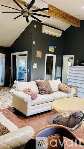 A living room with a white couch and a ceiling fan.
