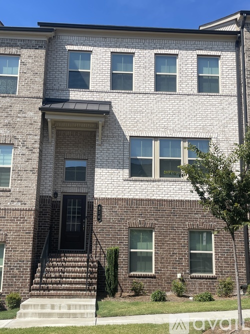 A two-story brick building with a black door and steps leading up to it.