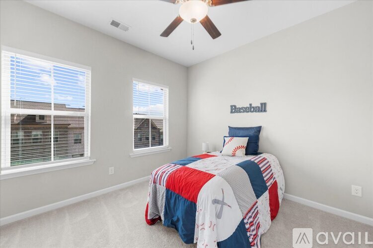 A bedroom with a bedspread featuring a baseball theme.