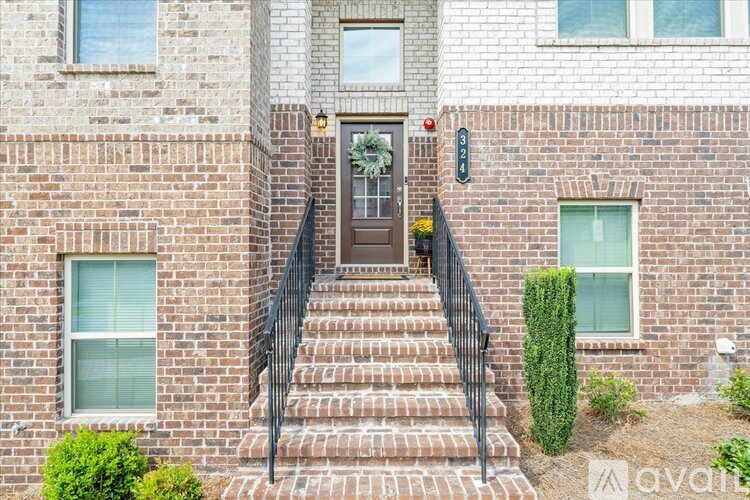 A brick house with a black metal staircase leading to the front door.