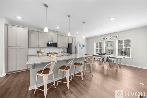 A kitchen with a dining table and chairs in front of a Farmhouse sign.