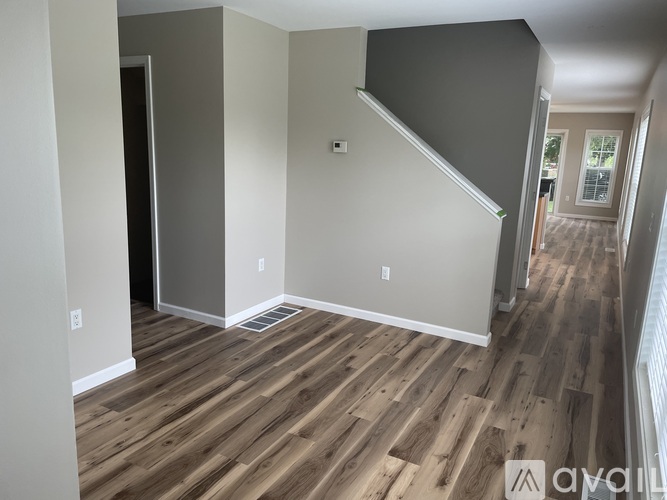 A room with wooden floors and a staircase leading to another room.