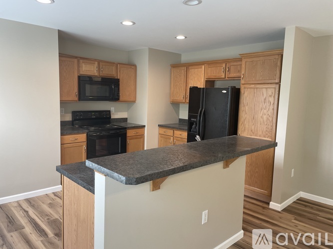 A kitchen with wooden cabinets and a black refrigerator.