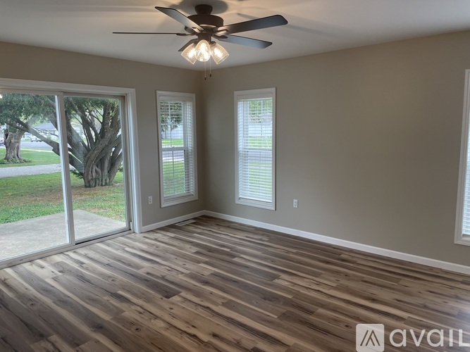A room with a ceiling fan and sliding glass doors.