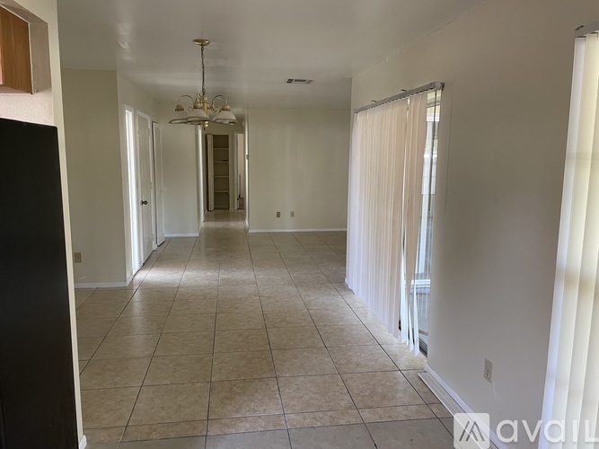 A spacious room with tiled flooring and a chandelier hanging from the ceiling.