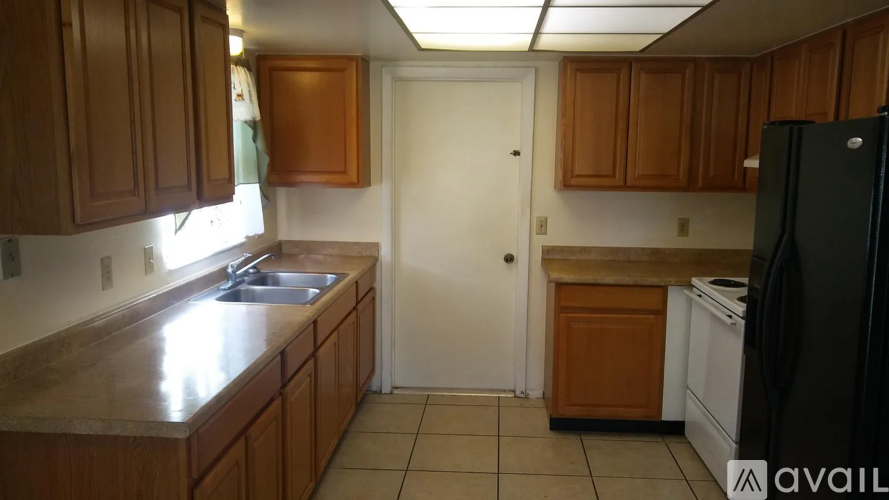 A kitchen with wooden cabinets and a black refrigerator.