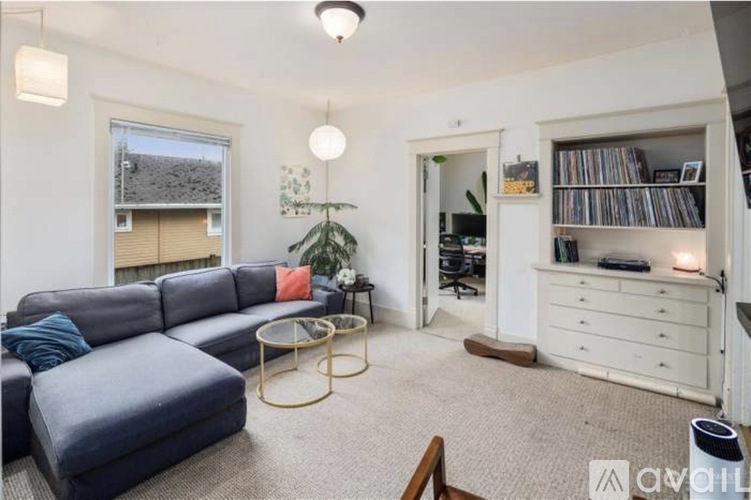 A living room with a grey sofa, a coffee table, and a bookshelf.
