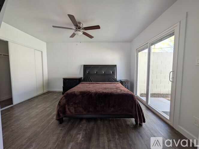 A bedroom with a bed, dresser, and sliding glass doors.