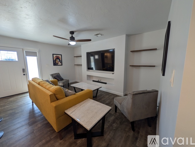 A living room with a yellow couch and a flat screen TV mounted on the wall.
