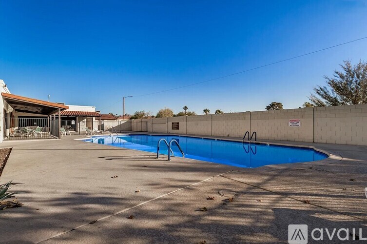A large outdoor swimming pool with a diving board and a building in the background.