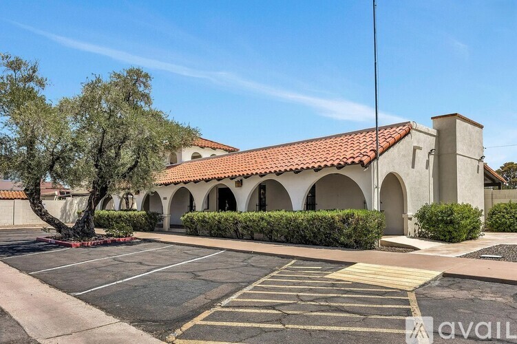 A building with a red tile roof and a parking lot in front.