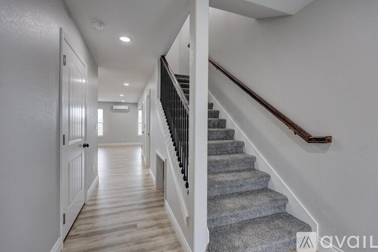 A hallway with a staircase and a door on the left.