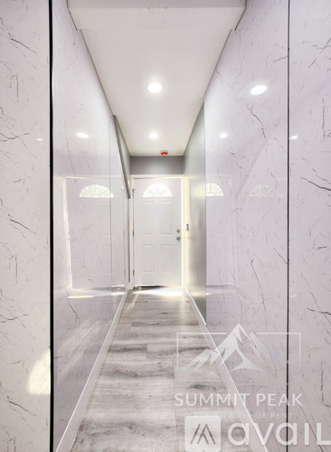 A hallway with marble walls and floors leading to a door at the end.