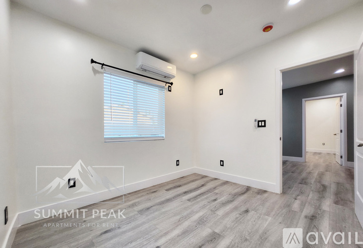 A spacious room with a window, a door, and a wall-mounted air conditioner unit.