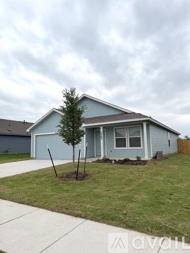 A small blue house with a white fence and a tree in front.