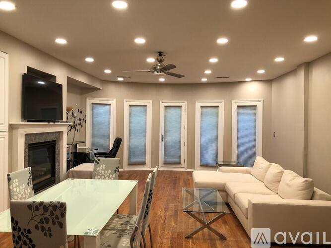 A modern living room with a glass table and a television on the wall.