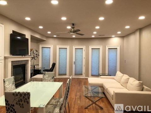 A modern living room with a glass table and a television on the wall.