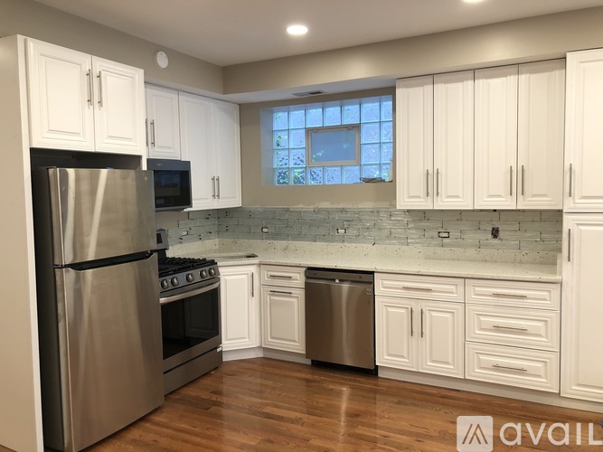 A kitchen with white cabinets and a stainless steel refrigerator.