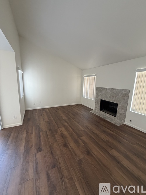 A room with wooden flooring and a fireplace.