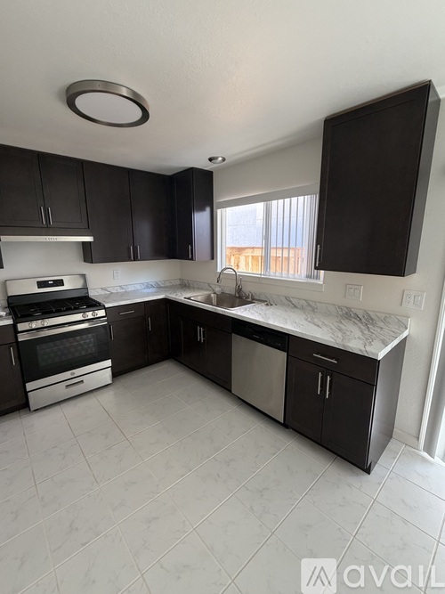 A kitchen with black cabinets and a marble countertop.