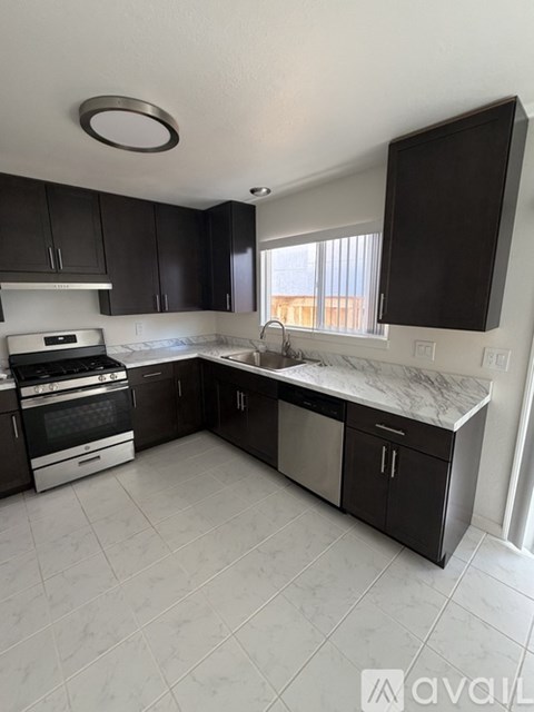 A kitchen with black cabinets and a marble countertop.