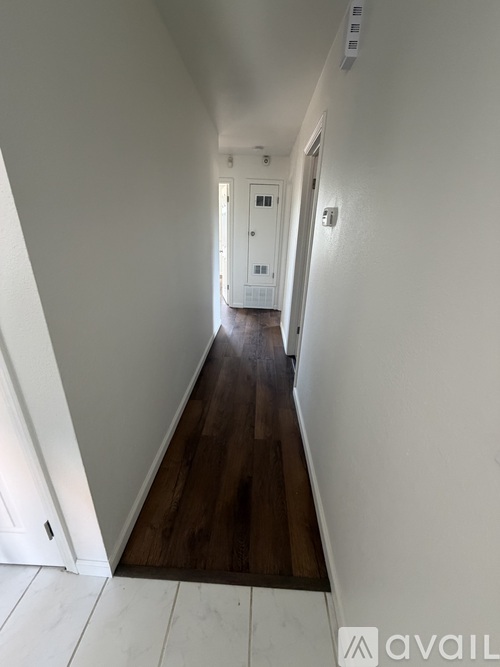 A long hallway with white walls and a wooden floor.