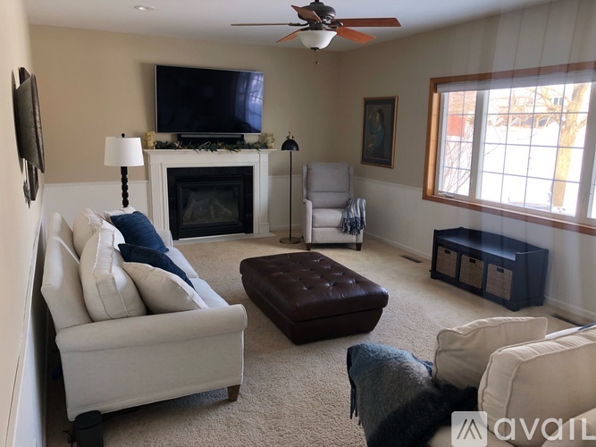 A living room with a fireplace, a chair, a couch, and a television.