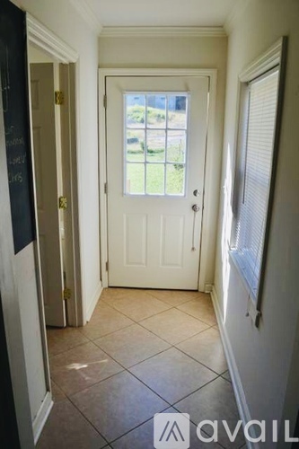 A hallway with a white door and tiled floor.