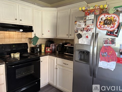 A kitchen with a black stove top oven and a refrigerator covered in magnets and papers.