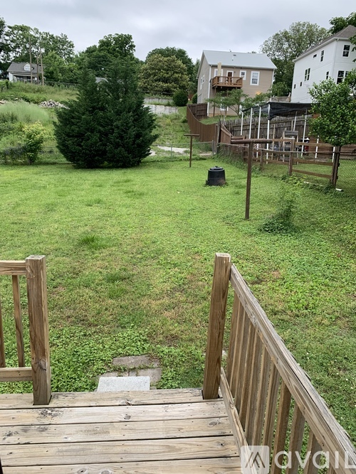 A wooden deck leads to a grassy area with a house in the background.