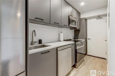 A modern kitchen with stainless steel appliances and white countertops.