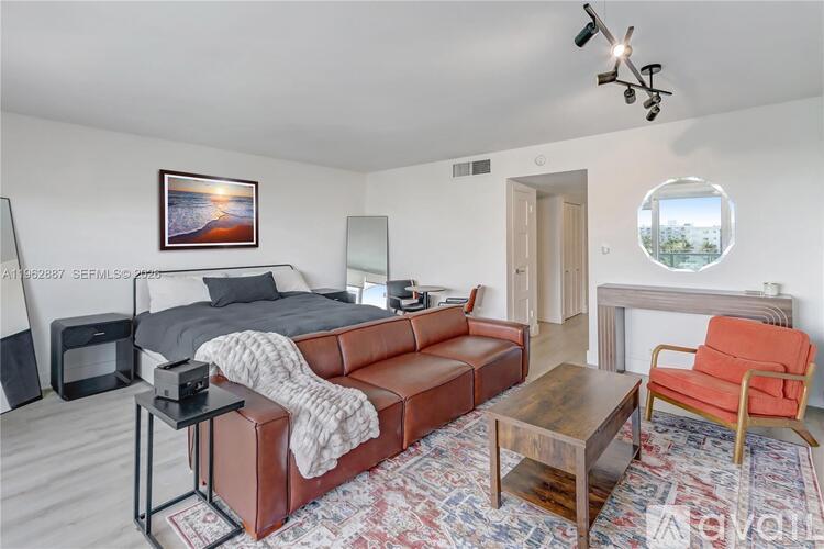 A bedroom with a bed, a couch, a chair, and a painting on the wall.