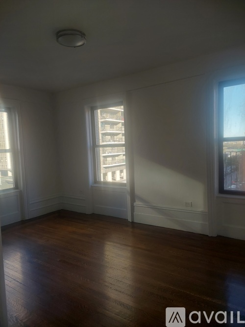 A room with wooden floors and two windows letting in light.