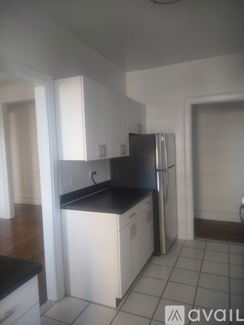 A kitchen with white cabinets and a black countertop.