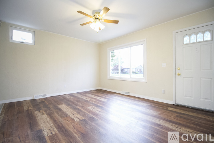 A room with a ceiling fan and wooden flooring.