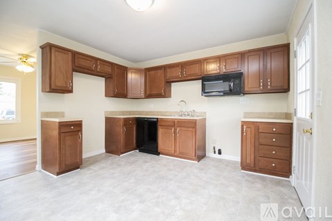 A kitchen with wooden cabinets and a black dishwasher.