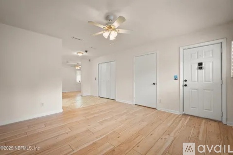 A spacious room with wooden flooring and white walls.